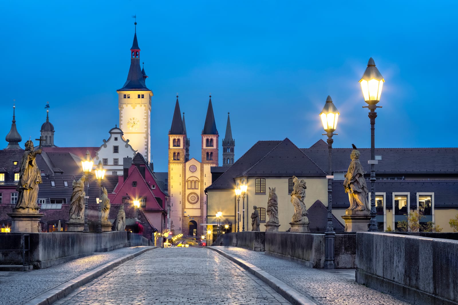Alte Mainbrücke in Würzburg in der Abenddämmerung mit Heiligenfiguren, Dom und Rathausturm