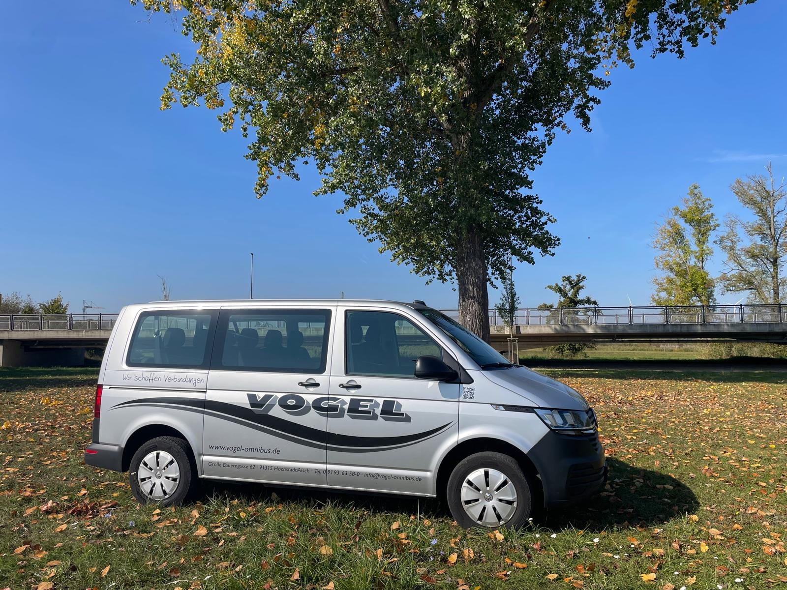Kleinbus von Vogel-Omnibus in der Seitenansicht unter einem Baum