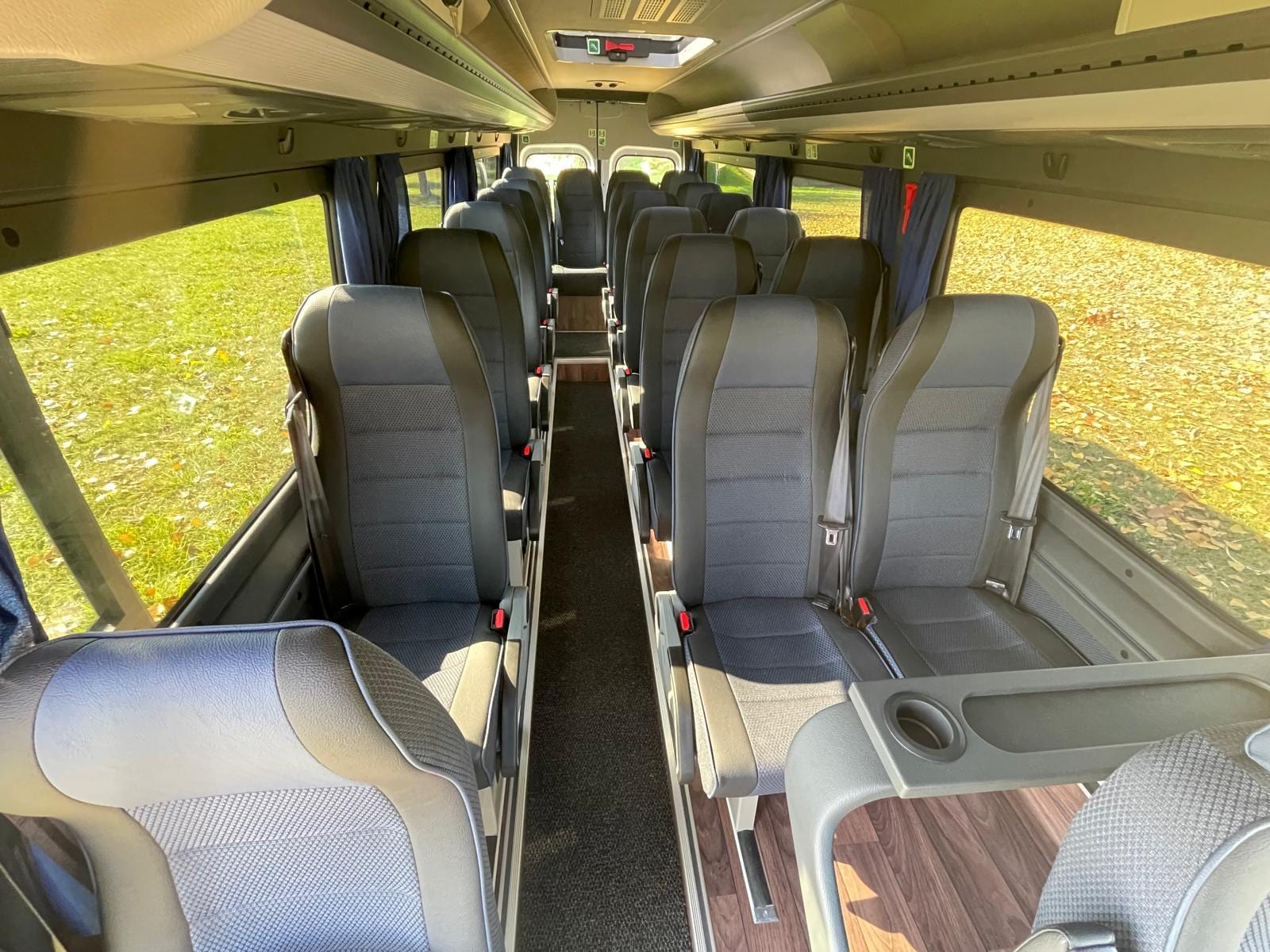 Innenraum des Komfort Midibus mit gepolsterten Sitzreihen und Gepäckablagen