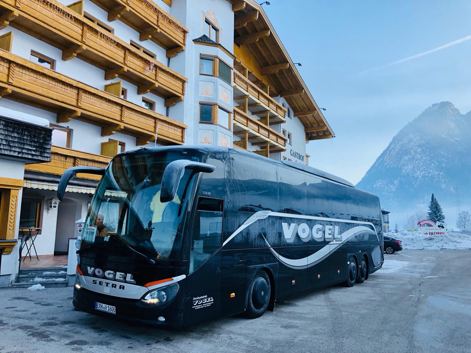 Vogel-Reisebus im Winter vor einem Alpenhotel: Skireisen und Winterfahrten