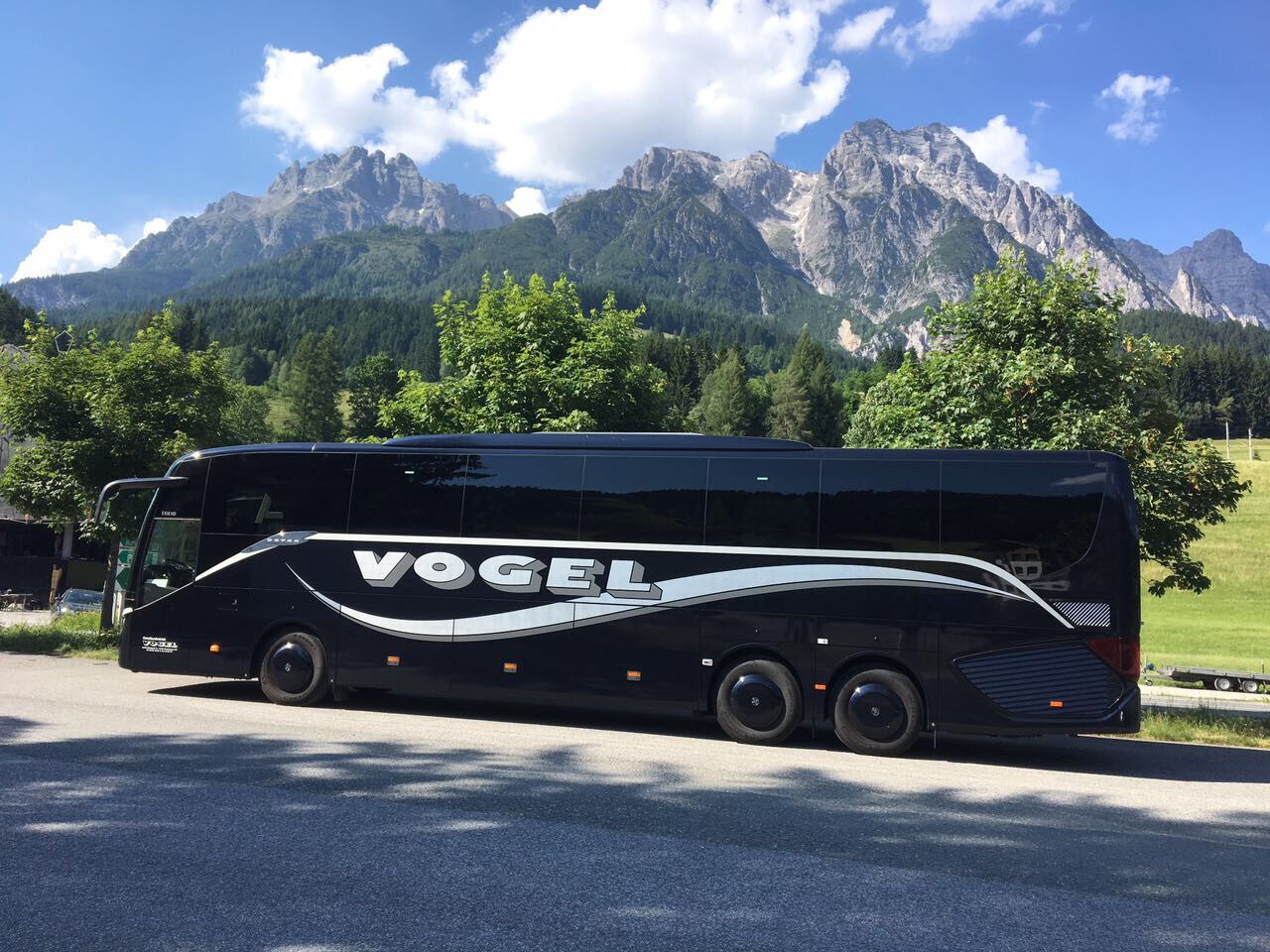 Vogel-Reisebus vor einem Bergmassiv: Busreisen nach Südtirol und in die Dolomiten