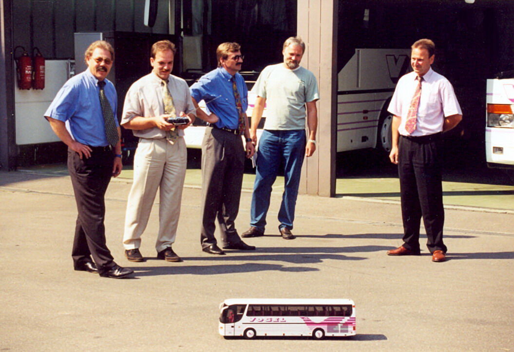 Das Team von Vogel-Omnibus mit einem Modellbus auf dem Betriebshof